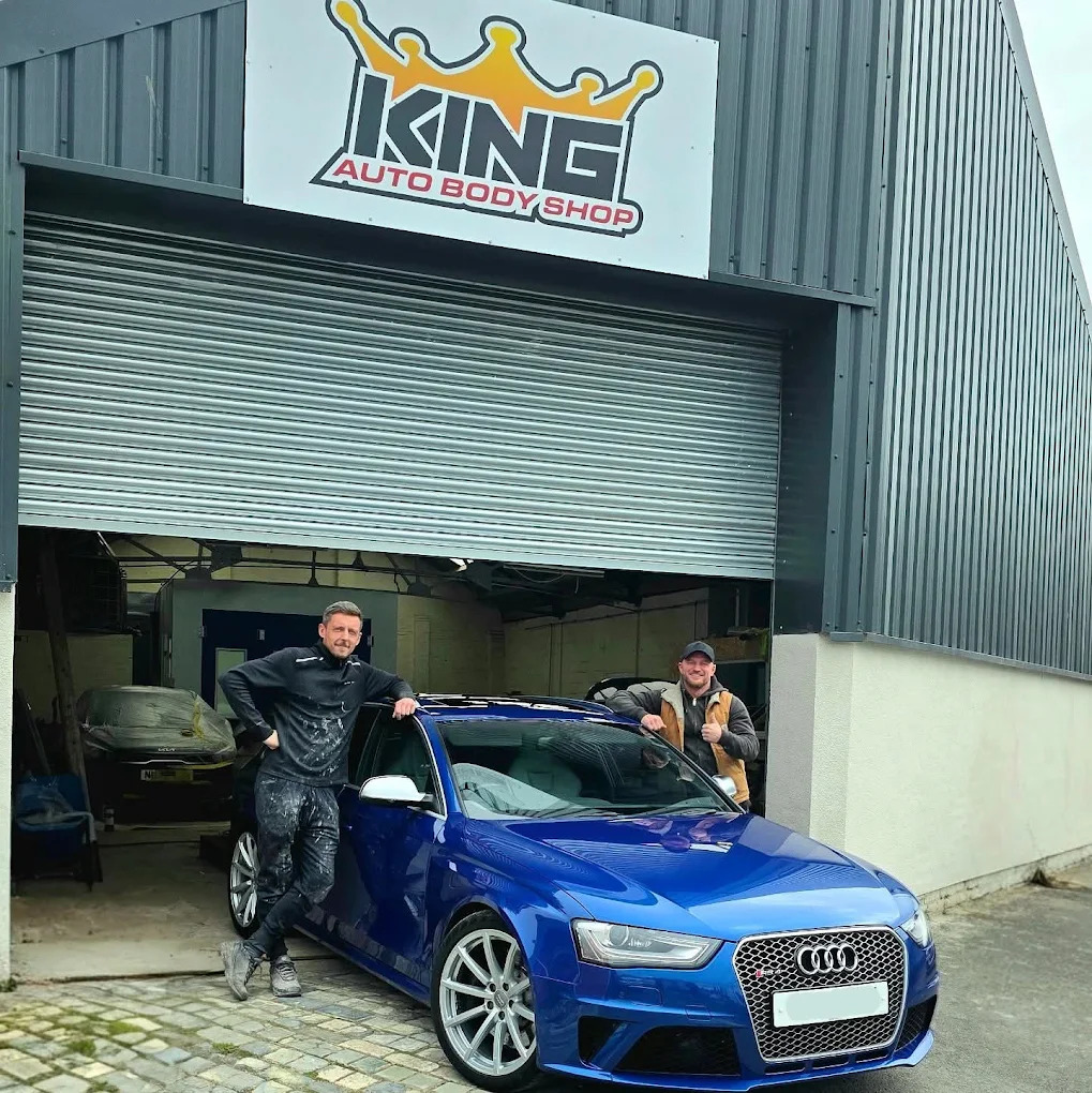 Two technicians with a finished blue Audi outside the King Auto Body Shop workshop